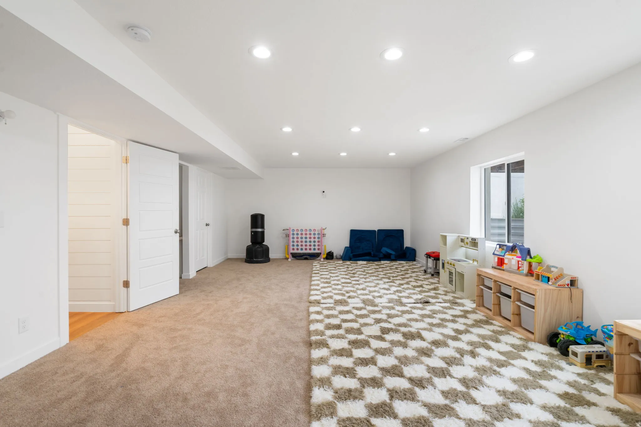 Spacious interior room featuring light-toned carpeting and recessed lighting