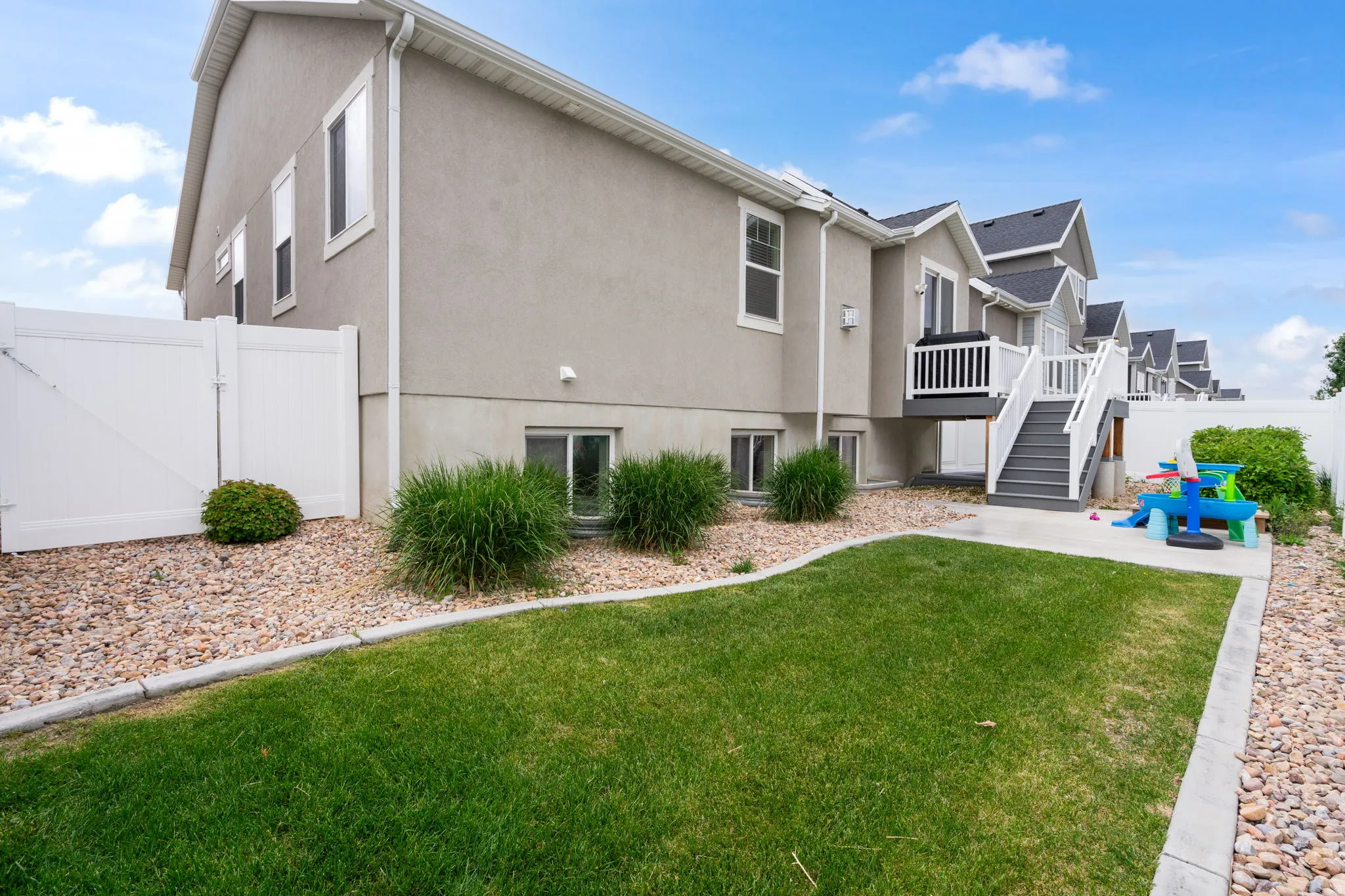 Expansive rear yard featuring a manicured lawn, gravel landscaping, and mature shrubbery