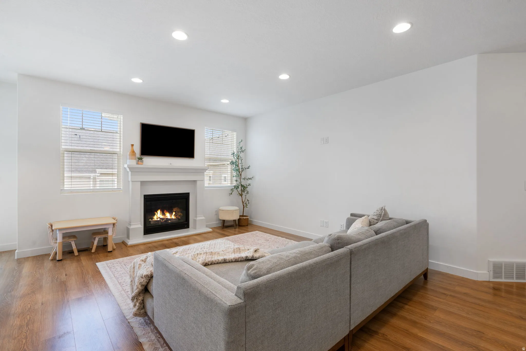 Living space featuring wood-finish flooring, recessed lighting, white walls, and a fireplace with a white mantel