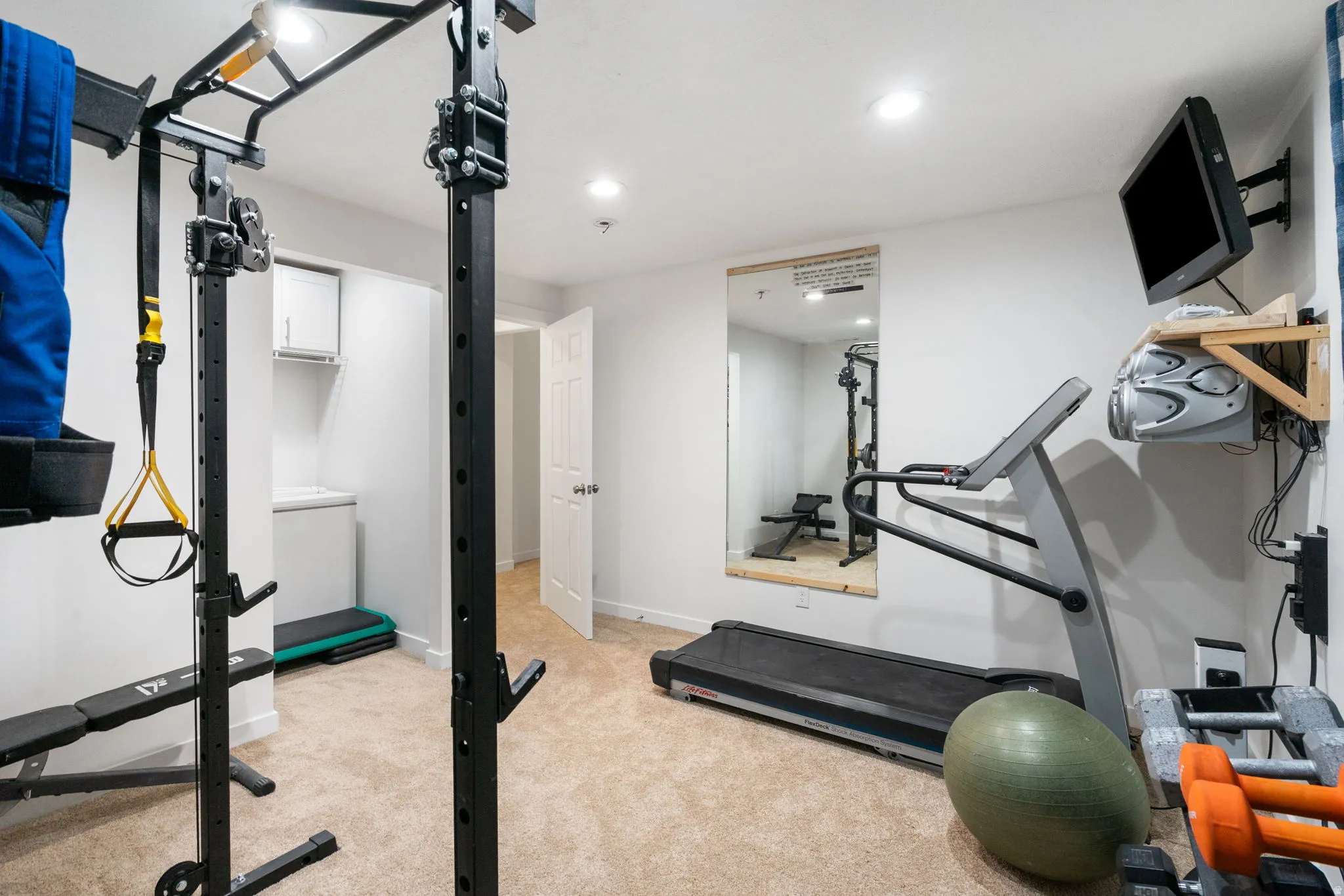 Dedicated fitness area featuring recessed lighting, a built-in storage cabinet, and a full-length wall mirror