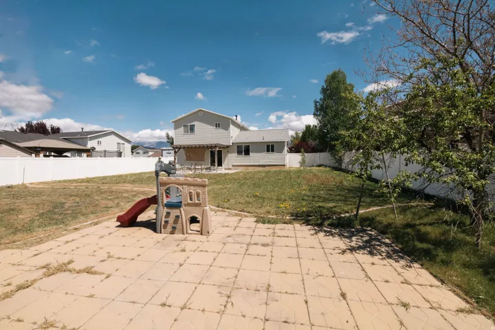 Rear view of house featuring a patio area, a fenced backyard, and a playground