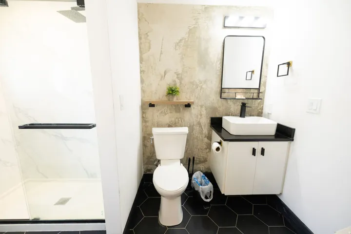 Bathroom with vanity, a marble finish shower, and dark tile patterned flooring
