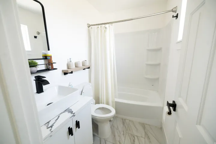 Bathroom featuring vanity, shower / bathtub combination with curtain, and light marble finish floors