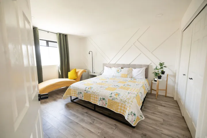 Bedroom with wood finished floors, a decorative wall, and a closet
