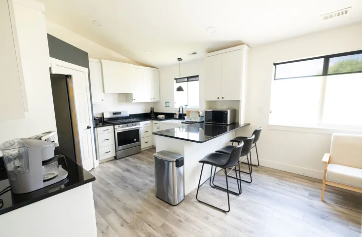 Kitchen with white cabinets, stainless steel appliances, a peninsula, a kitchen breakfast bar, and lofted ceiling