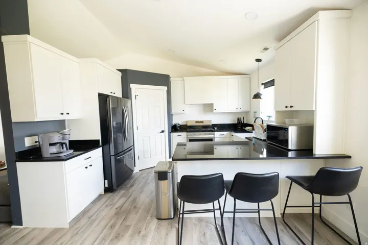 Kitchen featuring a peninsula, freestanding refrigerator, white cabinetry, pendant lighting, and stainless steel range with gas stovetop