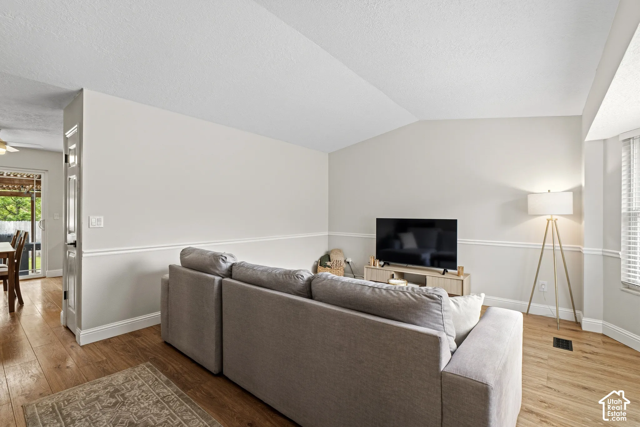 Spacious living area featuring wood-finish flooring, vaulted ceiling, and chair rail molding