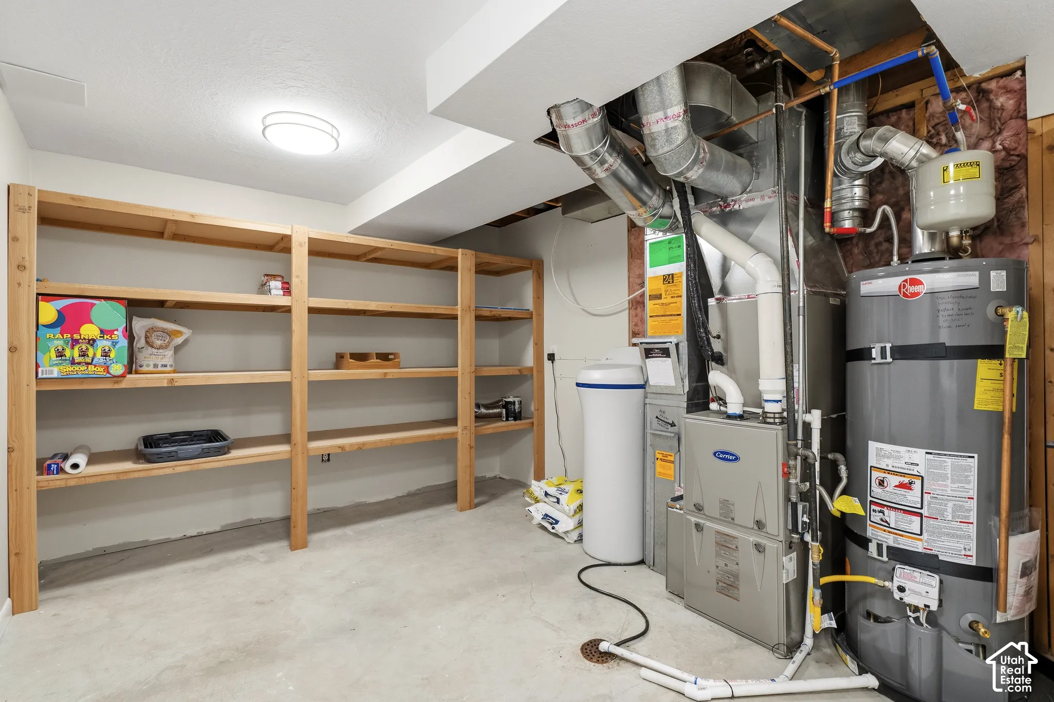 Basement utility space featuring a water heater, furnace, water softener, and extensive built-in wooden shelving for organized storage