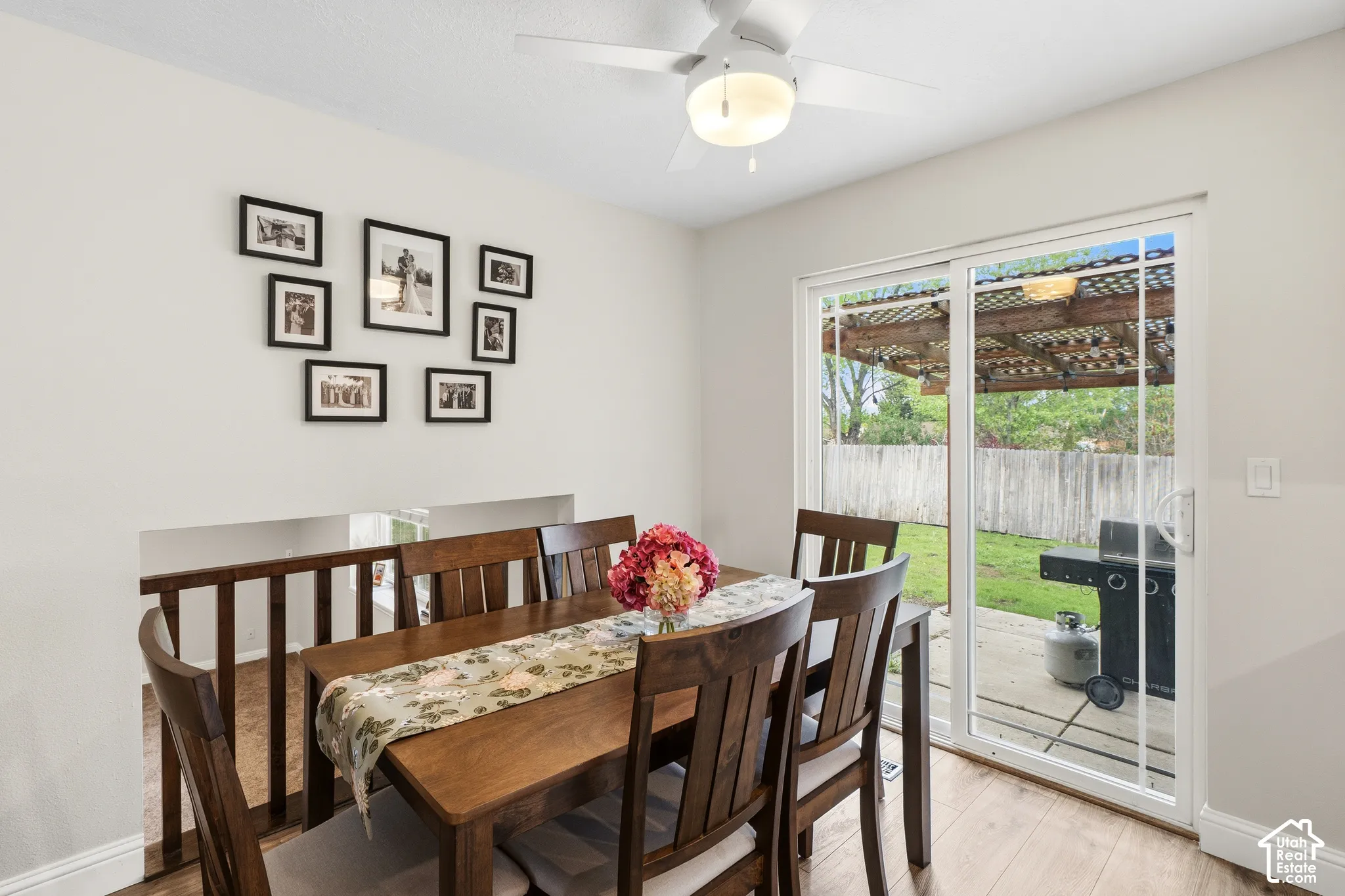 Dining area featuring wood-finish flooring, a ceiling fan with integrated lighting, and a half-wall with wood railing