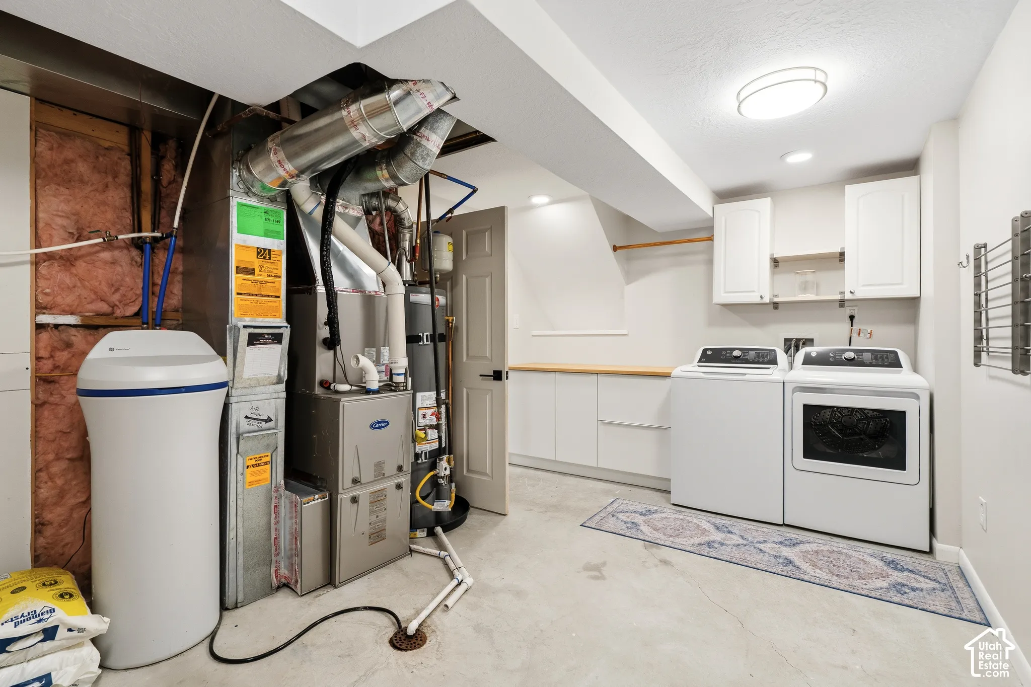 Dedicated laundry area featuring white cabinetry, a wood-finish countertop, and a built-in drying rack