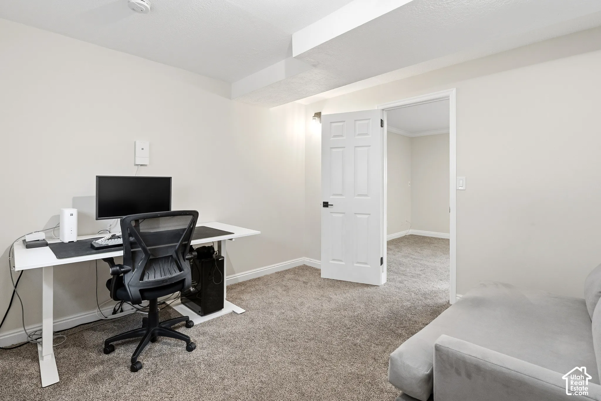 Carpeted room with light neutral walls, white trim, and a six-panel interior door with matte black hardware