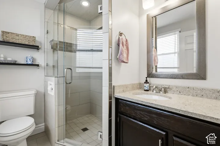 Contemporary bathroom featuring a glass-enclosed shower with tile surround and integrated shelving, a dark wood-finish vanity with a light-toned countertop, and a framed mirror