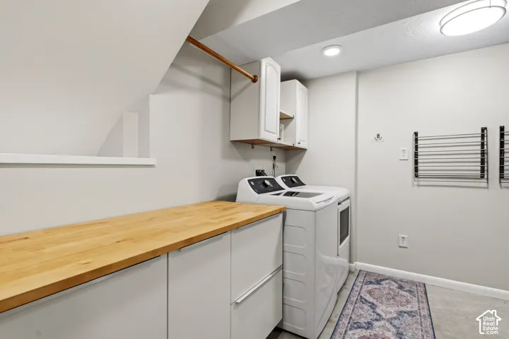Dedicated laundry area featuring a wood-finish countertop, white cabinetry, and built-in drying racks