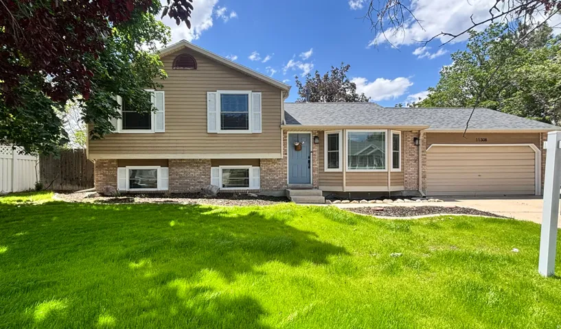 Split-level residence featuring a two-car garage, bay window, and a light blue front door