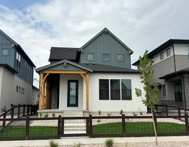 Contemporary exterior featuring white stucco, board and batten siding, multiple windows, an inviting covered porch with wood beams, and a fenced front yard with gravel and artificial turf