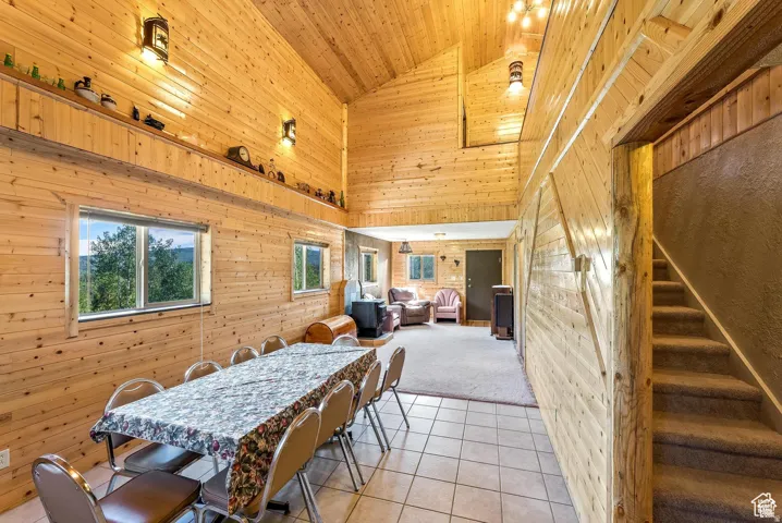 Vaulted wood-paneled ceiling, wood-finish walls, ceramic tile flooring, wood-burning stove, and a carpeted staircase