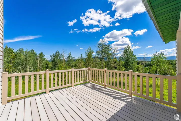 Expansive outdoor deck with composite decking and light-toned railing, offering sweeping natural scenery with mature trees and distant hills