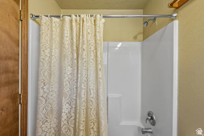 White shower surround with integrated soap dish, chrome shower head, and chrome single-handle faucet