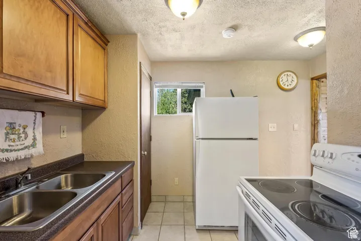 Kitchen featuring wood-finish cabinetry, a double-basin stainless steel sink, and a window