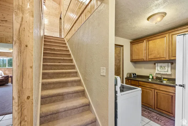 Carpeted stairway with natural wood newel post and wood-paneled walls