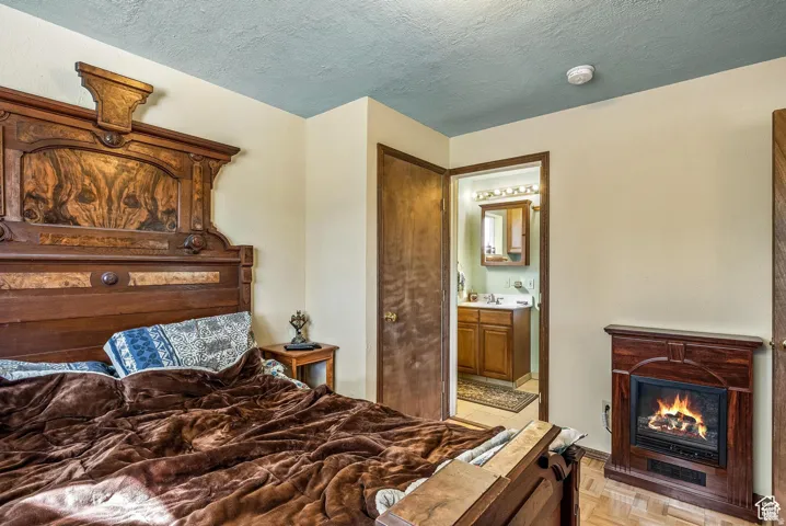 Bedroom featuring a decorative wood-finish headboard, a built-in fireplace, and wood-finish flooring