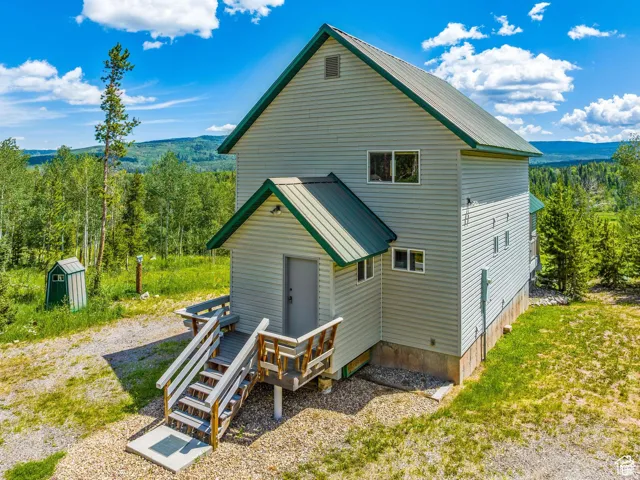 Vertical-sided structure featuring green metal roofing and light-colored siding