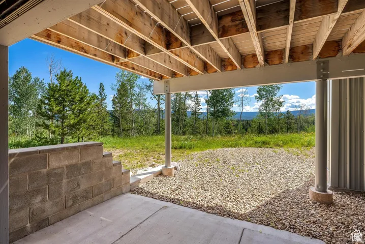 Covered outdoor patio with a concrete slab, gravel, and a visible wood joist ceiling