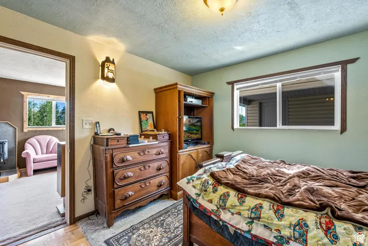 Bedroom with a single window featuring wood trim, a built-in media cabinet, and a wall-mounted sconce