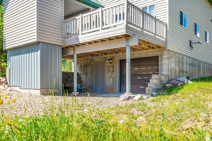 Exterior featuring light beige horizontal siding, a balcony with white railing, and a ground-level garage door