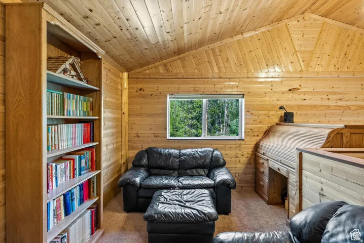Wood-paneled room featuring a vaulted ceiling with exposed beams, a built-in wood bookshelf, and a built-in roll-top desk