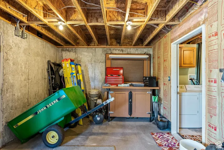 Unfinished basement featuring exposed joists, concrete walls, a built-in workbench, and roughed-in insulation for future finishing