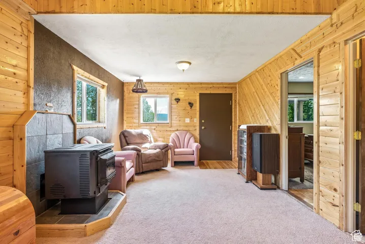 Interior space featuring wood paneling throughout, a slate-tiled hearth with a wood-burning stove, and dual windows providing natural light