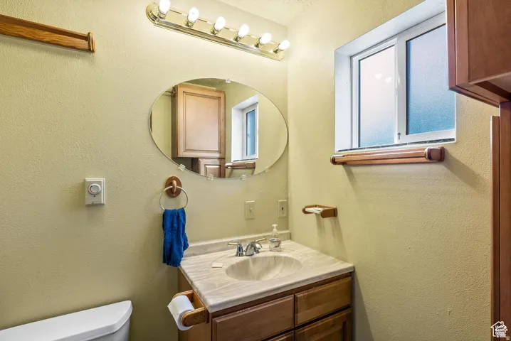 Bathroom vanity with an oval mirror, polished chrome lighting fixture, and a single-pane window
