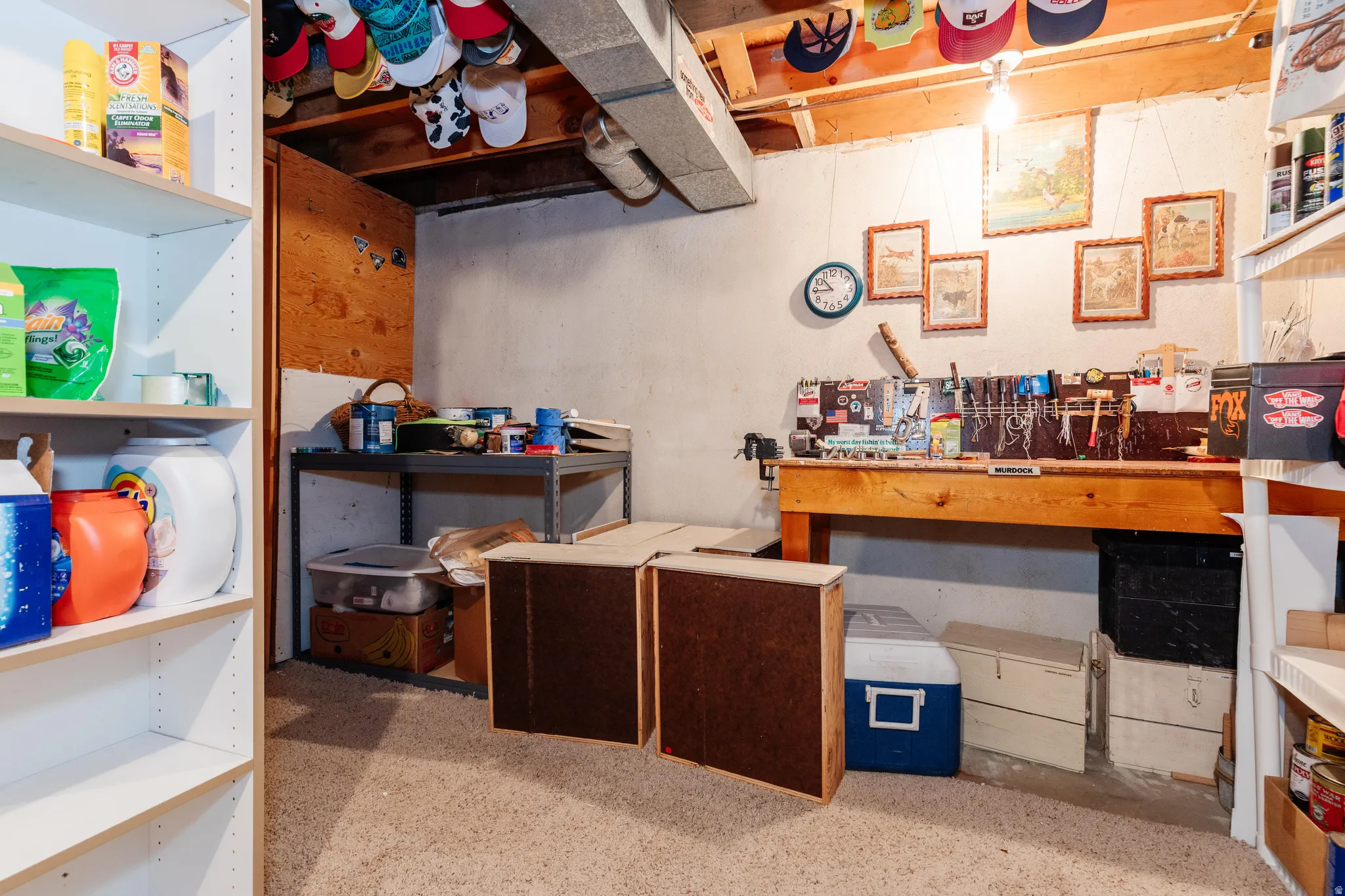 Lower level utility space featuring a built-in workbench, exposed ceiling joists, and shelving units