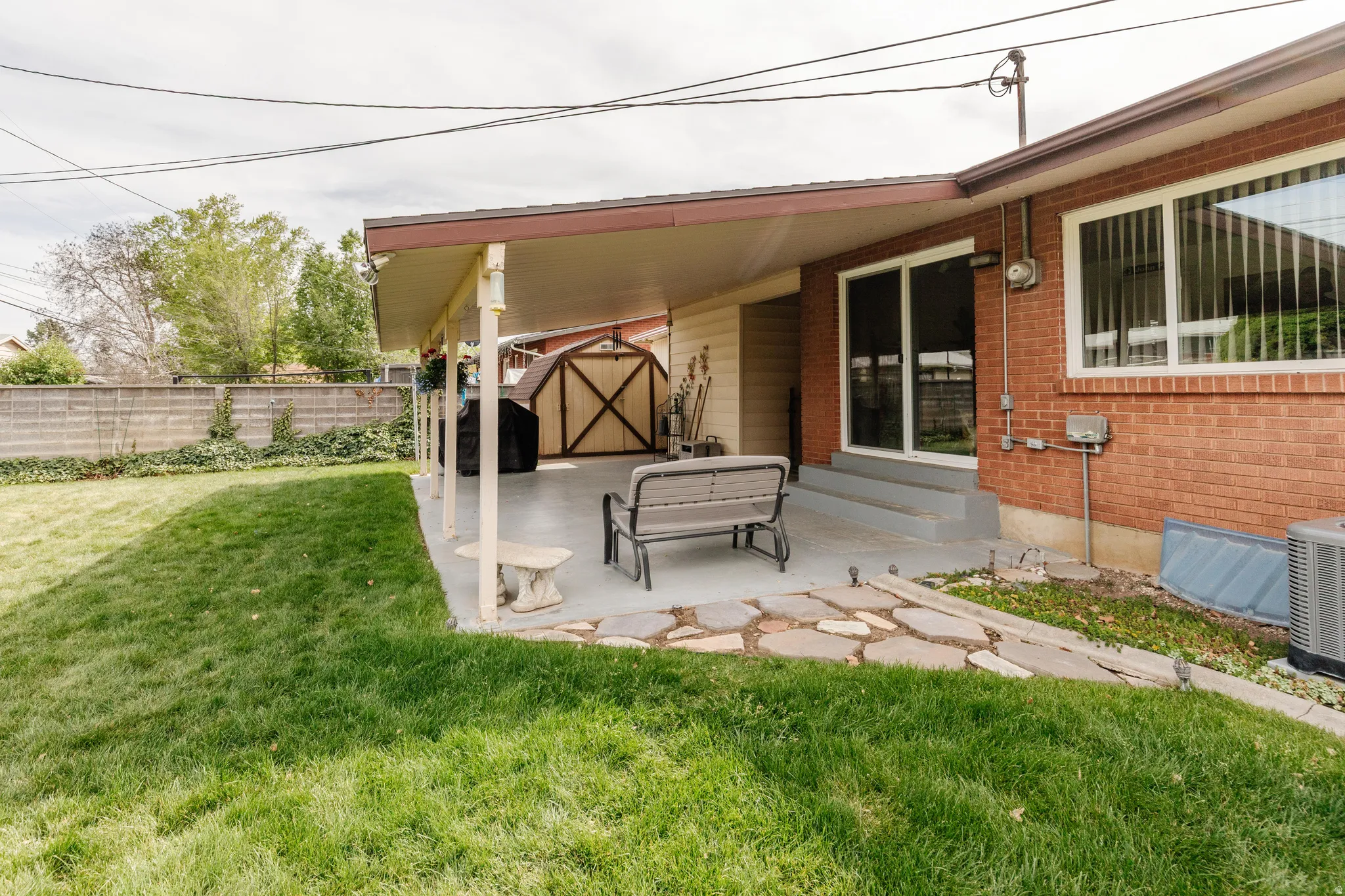 Expansive backyard featuring a covered patio, manicured lawn, and a wooden privacy fence
