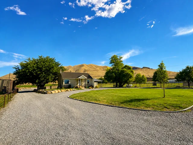 Gravel driveway with a dedicated parking area, established trees, and a manicured lawn