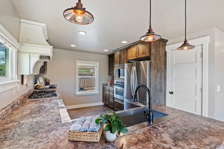 Kitchen featuring wood-finish cabinetry, stainless steel appliances, a gas cooktop, and a built-in oven