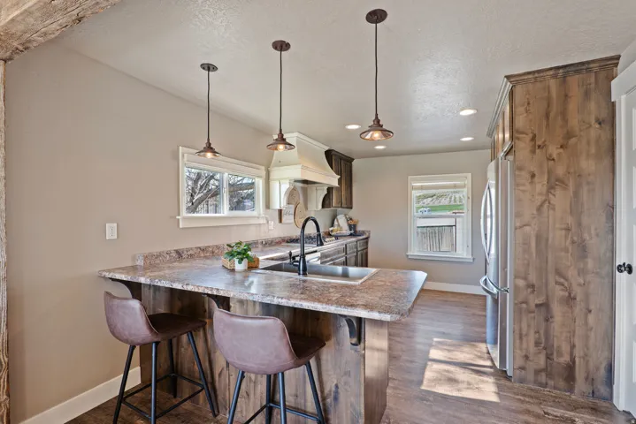 Spacious kitchen featuring a peninsula with seating, stainless steel appliances, wood-finish flooring, and recessed lighting