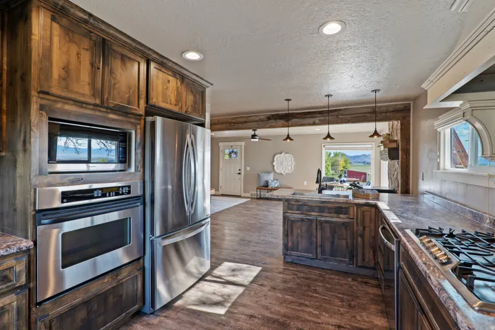 Kitchen featuring wood cabinetry, stainless steel appliances, a built-in oven and microwave, and wood-finish flooring