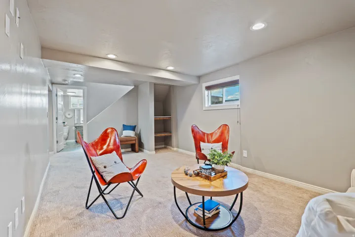 Recessed lighting illuminates this carpeted area featuring a built-in staircase with open shelving underneath