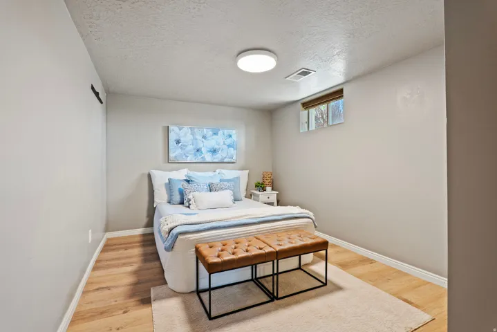 Bedroom featuring light wood-finish flooring, light neutral-toned walls, and a recessed window with blinds