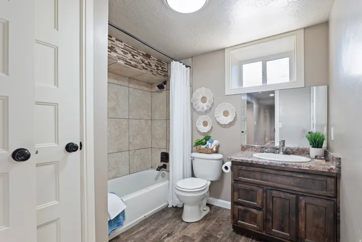 Bathroom featuring a wood-finish vanity with an integrated sink and stone-look countertop