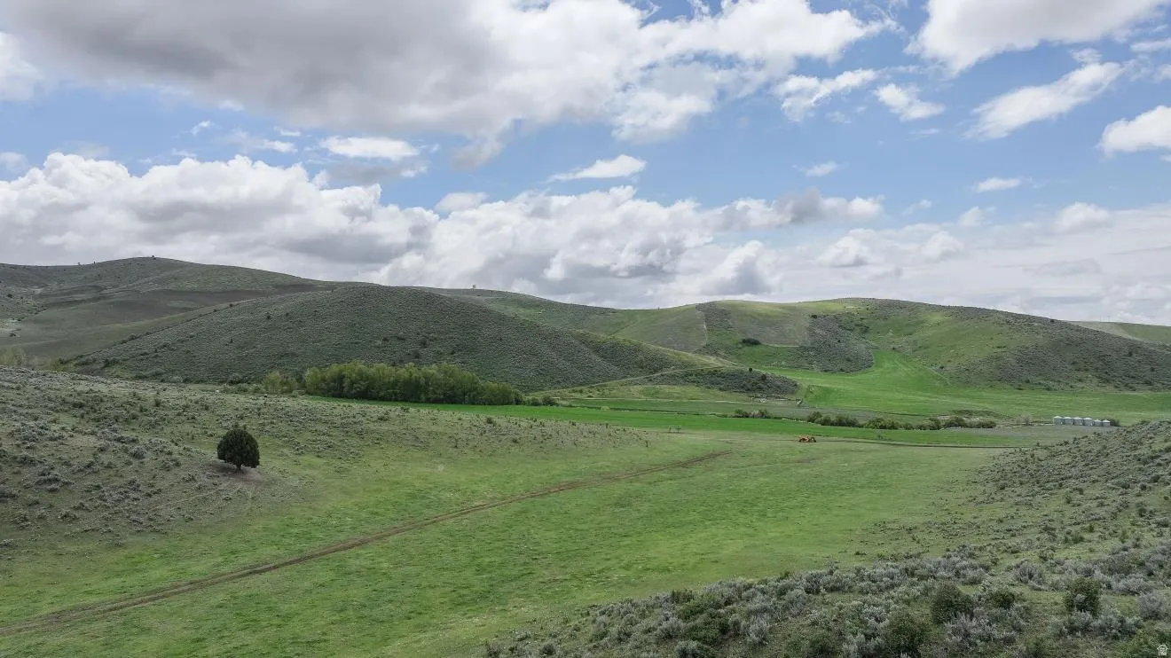 Expansive landscape featuring rolling green hills and distant agricultural structures