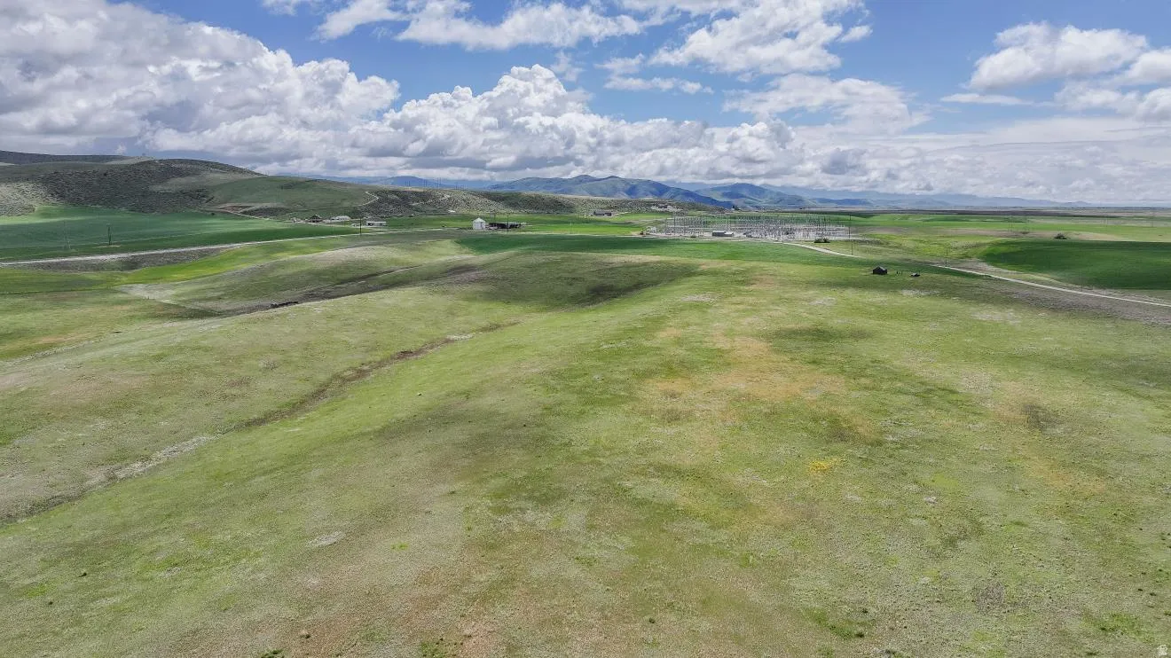 Expansive green fields featuring rolling hills and distant mountains