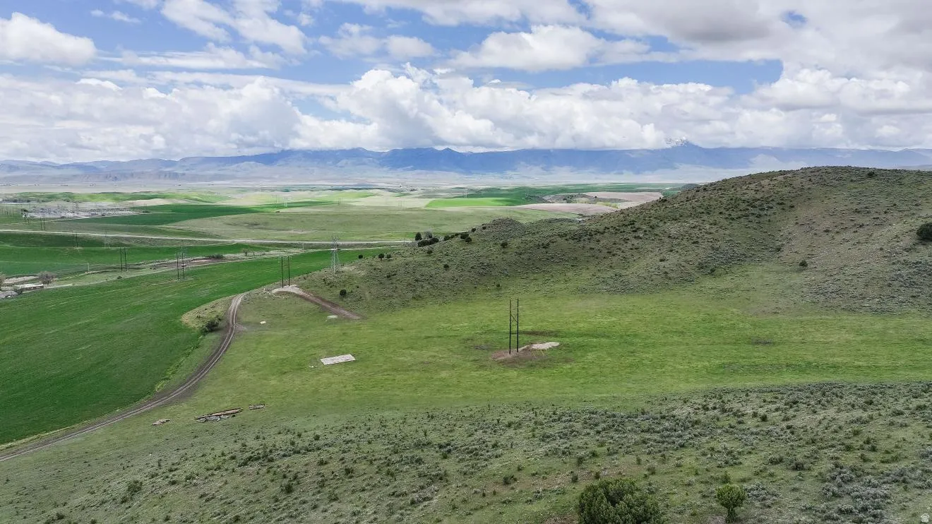 Expansive rural landscape featuring rolling hills and distant mountains under a cloudy sky