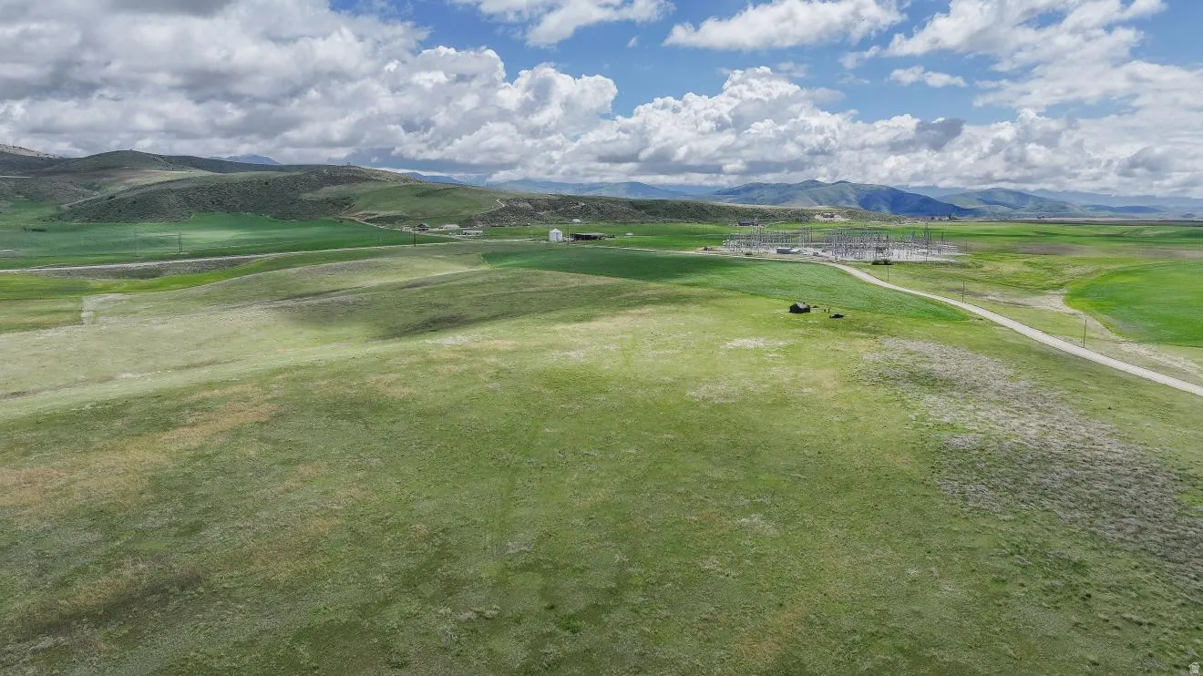 Expansive green terrain featuring gently rolling hills and distant mountains