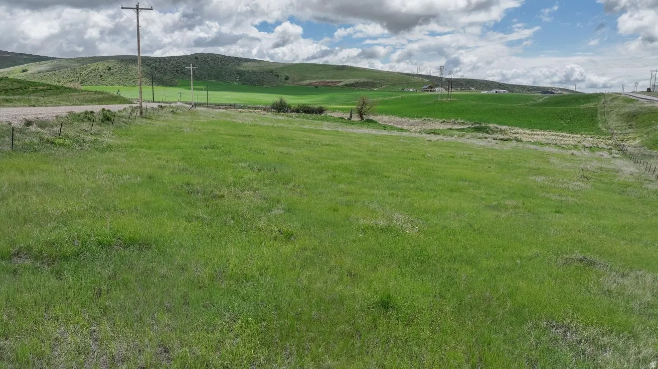 Expansive green acreage featuring a gently rolling landscape and distant hills