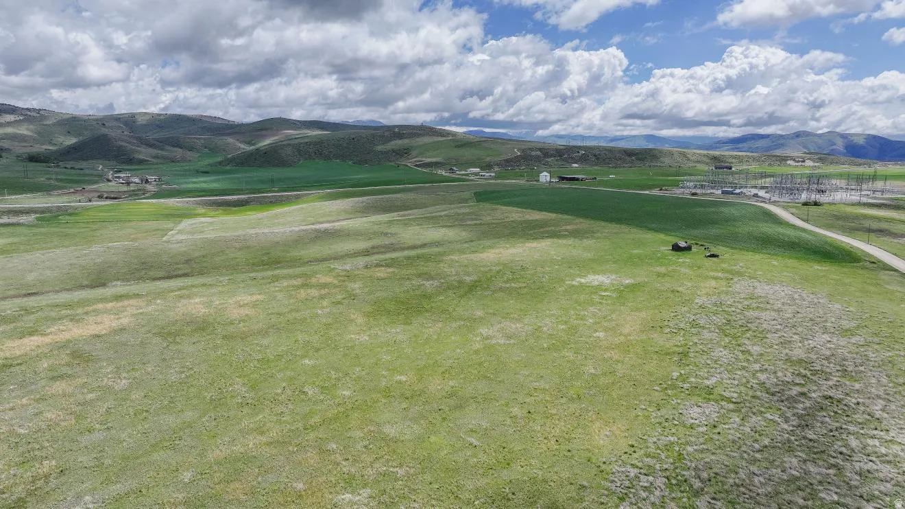 Expansive green terrain with distant rolling hills and a scattered rural landscape