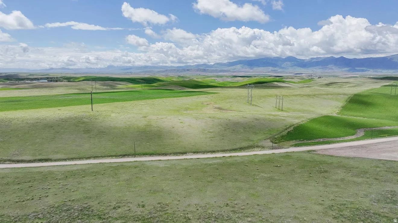 Expansive rural landscape featuring rolling green hills and distant mountains