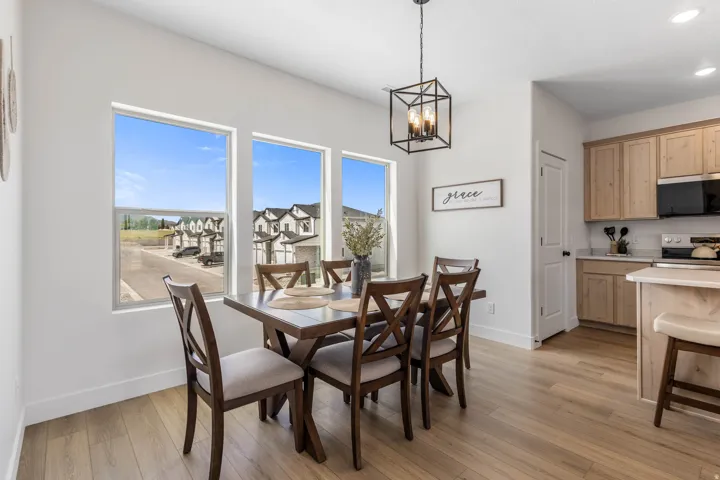 Dining area featuring three large windows, a linear chandelier, and wood-finish flooring